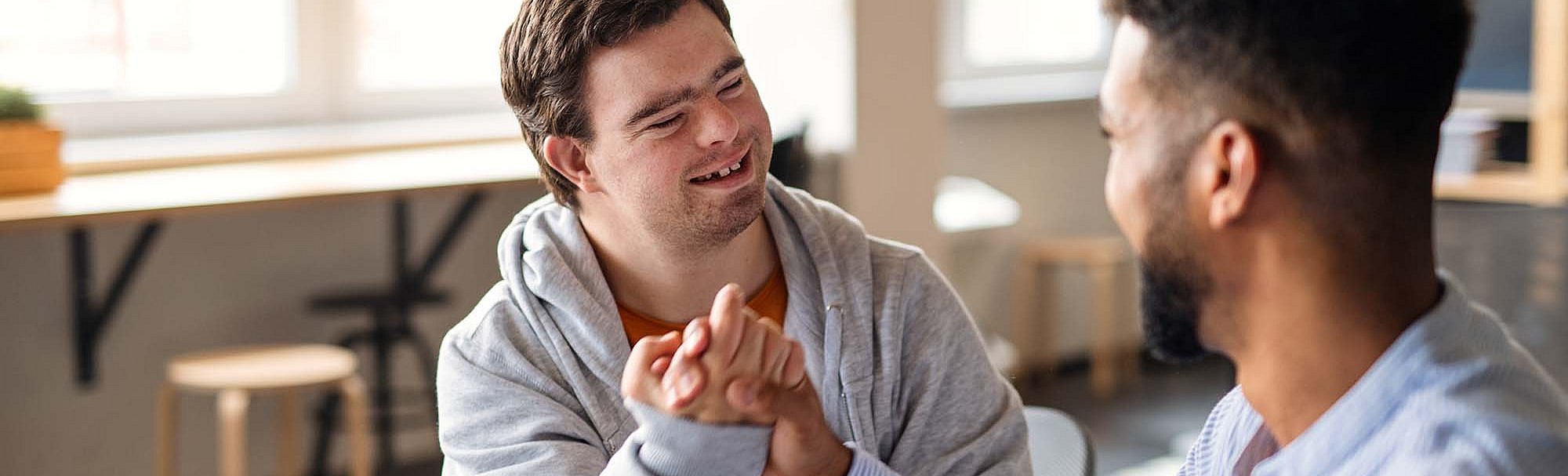 Zwei Männer, einer davon mit Down Syndrom, machen einen Bro-Handshake